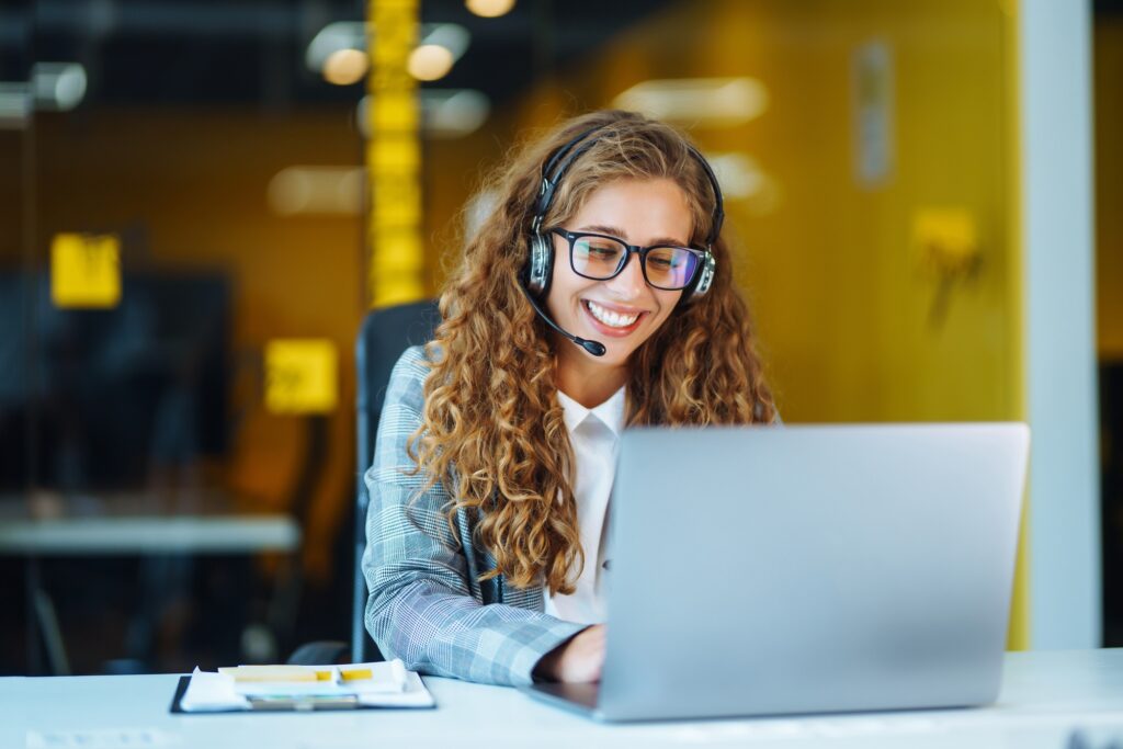 An IT support specialist with headset working on support hotline in an office via video conference.