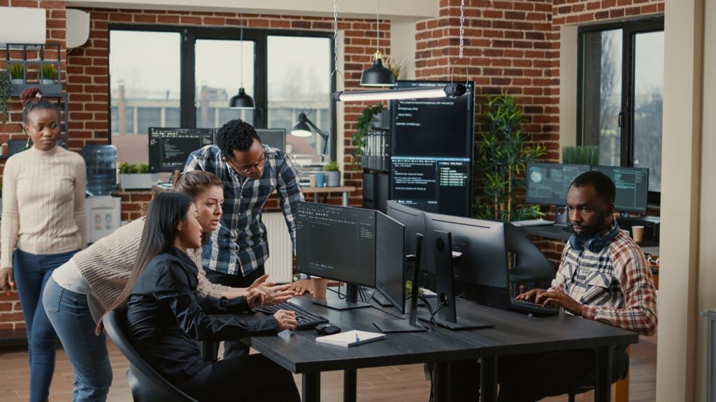 Junior DevOps engineers collaborating on group project compiling algorithm and asking senior developer.