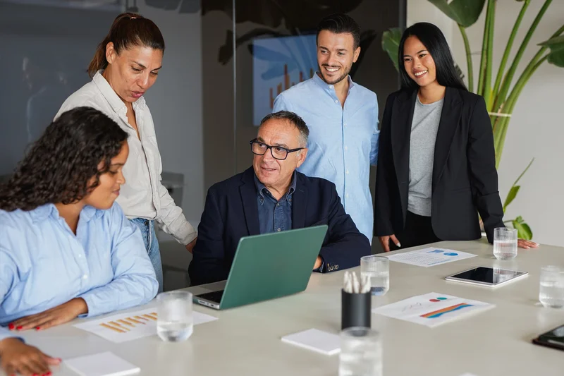 A team of professionals meeting around a laptop to discuss hiring needs across finance, SaaS, and enterprise IT, supported by a Toronto IT staffing agency.